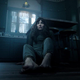 A frightened woman sits on the floor of a dark kitchen in James Wan's new horror movie, Malignant.